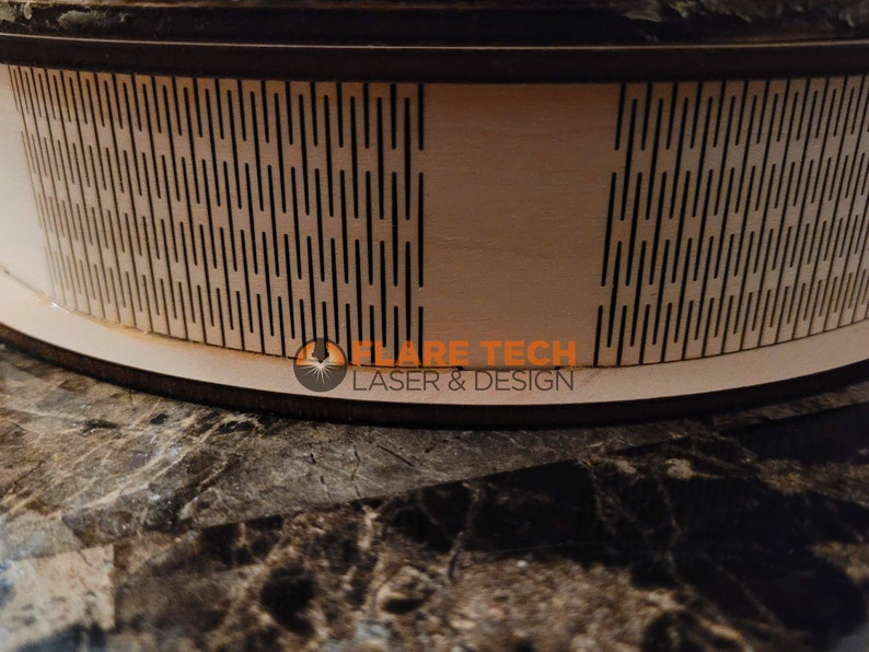 Peut inclure: Gros plan d'un cercle en bois avec un motif g&eacute;om&eacute;trique d&eacute;coup&eacute;. Le cercle est sur une surface brune. Le texte "FLARE TECH LASER & DESIGN" est visible sur le cercle.
