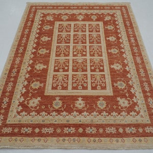 May include: A traditional rug with a red background and a beige pattern. The pattern features a central square with smaller squares inside, surrounded by a border of floral motifs.