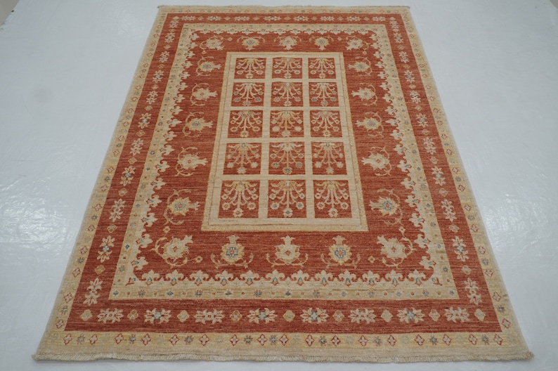 May include: A traditional rug with a red background and a beige pattern. The pattern features a central square with smaller squares inside, surrounded by a border of floral motifs.