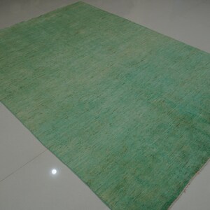 May include: A solid green rug with a subtle texture. The rug has a light green color at the top and a darker green color at the bottom.