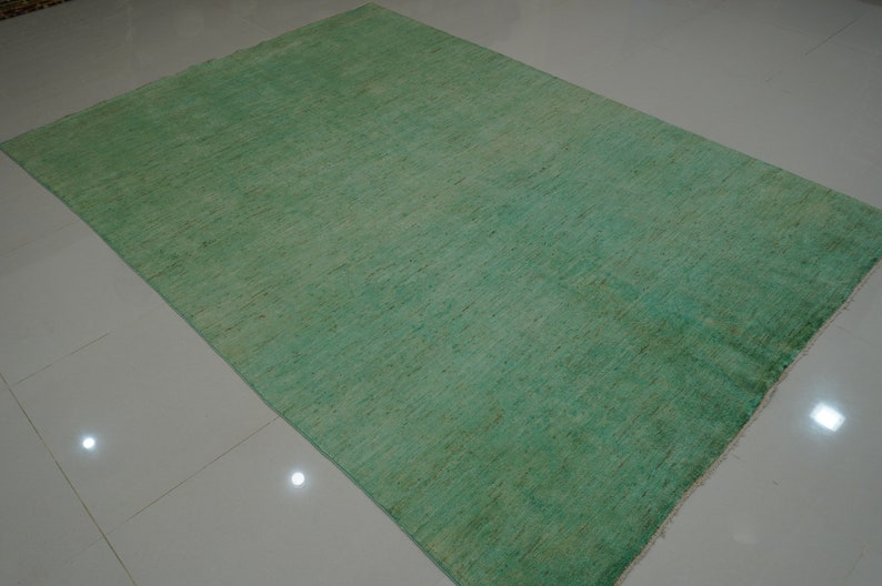May include: A solid green rug with a subtle texture. The rug has a light green color at the top and a darker green color at the bottom.