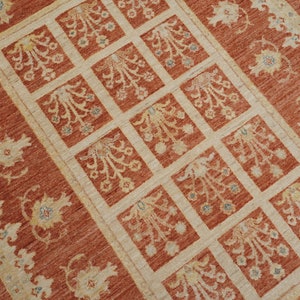 May include: A red and cream colored rug with a repeating pattern of stylized floral motifs. The rug has a border with a floral design.