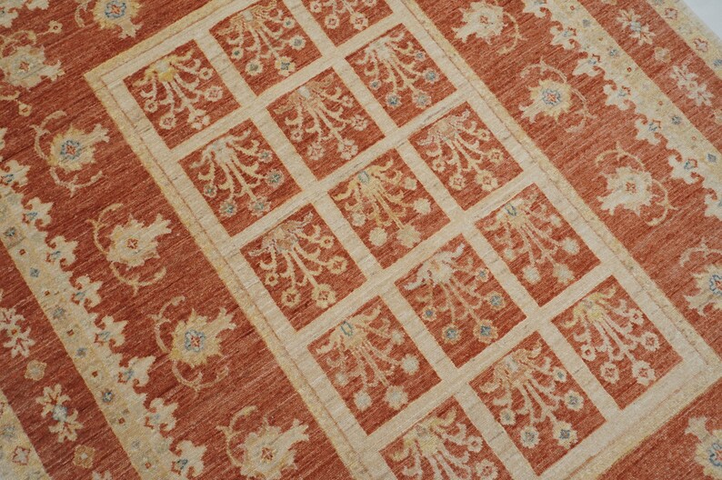 May include: A red and cream colored rug with a repeating pattern of stylized floral motifs. The rug has a border with a floral design.