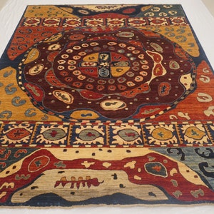 Op de afbeelding: Een kleurrijk tapijt met een centraal medaillonontwerp met ingewikkelde patronen en geometrische vormen. Het tapijt heeft een donkerblauwe achtergrond met accenten in rood, geel en beige.