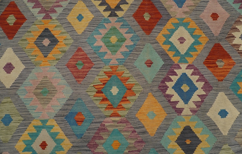 May include: A colorful rug with a geometric pattern in shades of blue, red, orange, yellow, green, and purple. The rug has a diamond-shaped design with intricate details.