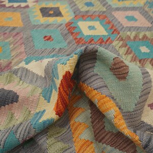 May include: A colorful rug with a geometric pattern in shades of orange, yellow, blue, green, and gray. The rug is woven with a traditional design and has a soft, textured feel.