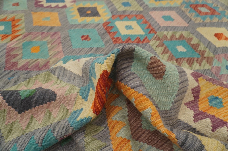 May include: A colorful rug with a geometric pattern in shades of orange, yellow, blue, green, and gray. The rug is woven with a traditional design and has a soft, textured feel.