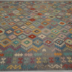 May include: A colorful rug with a geometric pattern in shades of blue, red, yellow, green, and pink. The rug has a traditional design with a repeating pattern of diamonds and triangles.