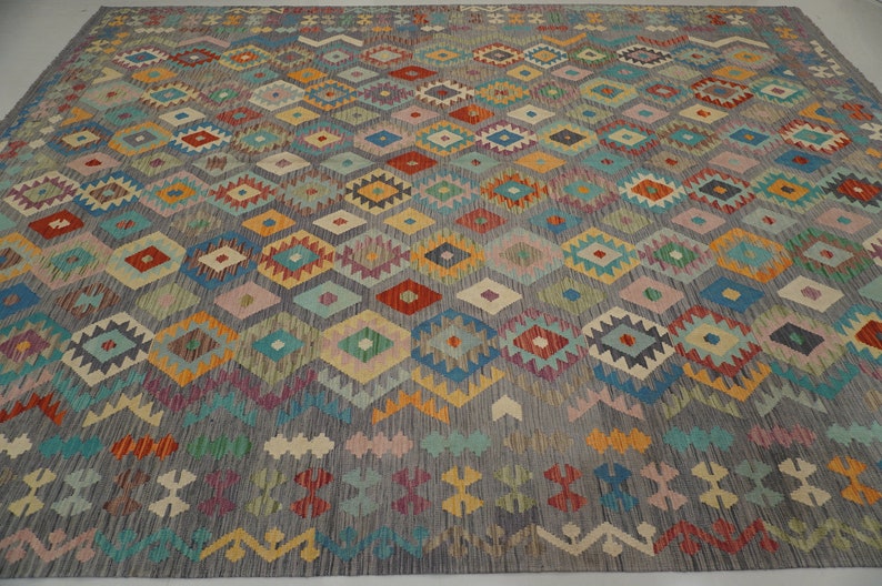 May include: A colorful rug with a geometric pattern in shades of blue, red, yellow, green, and pink. The rug has a traditional design with a repeating pattern of diamonds and triangles.