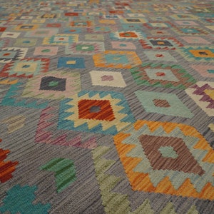 May include: A colorful rug with a geometric pattern in shades of blue, green, orange, red, and pink. The rug has a gray background and a diamond-shaped design.