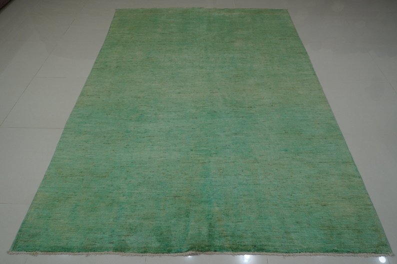May include: A solid green rug with a subtle texture. The rug has a slightly faded appearance, giving it a vintage look.