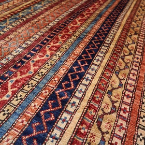 May include: A colorful rug with a geometric pattern in shades of red, blue, and beige. The rug has a striped design with intricate details.