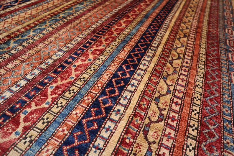 May include: A colorful rug with a geometric pattern in shades of red, blue, and beige. The rug has a striped design with intricate details.