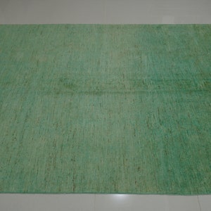 May include: A green area rug with a subtle, textured pattern. The rug has a slightly faded appearance, giving it a vintage look.