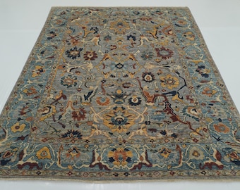 May include: A rectangular area rug with an intricate floral pattern. The rug features a gray background with a border of blue and yellow floral designs. The rug's design includes shades of blue, yellow, and red.