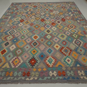 May include: A colorful rug with a geometric pattern in shades of red, blue, green, yellow, and orange. The rug has a gray background and a fringe border.