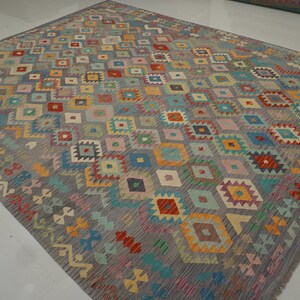 May include: A colorful rug with a geometric pattern in shades of blue, red, yellow, green, and pink. The rug has a gray background and a diamond-shaped pattern.