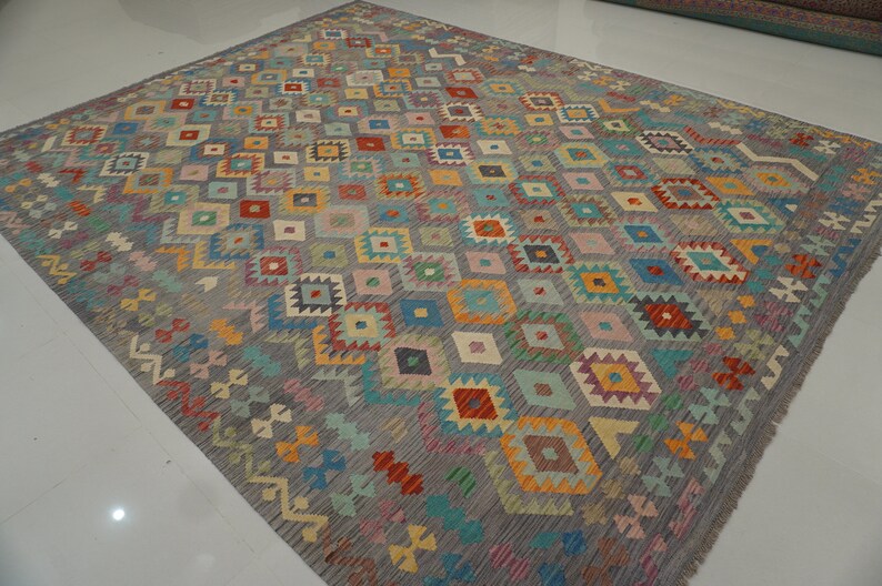 May include: A colorful rug with a geometric pattern in shades of blue, red, yellow, green, and pink. The rug has a gray background and a diamond-shaped pattern.