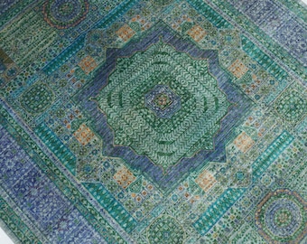 Può includere: Un tappeto dettagliato con un motivo complesso nelle tonalità del blu, verde e arancione. Il design incorpora forme geometriche e motivi floreali, dando un aspetto strutturato. La tavolozza dei colori e i motivi intricati suggeriscono uno stile tradizionale o bohémien.