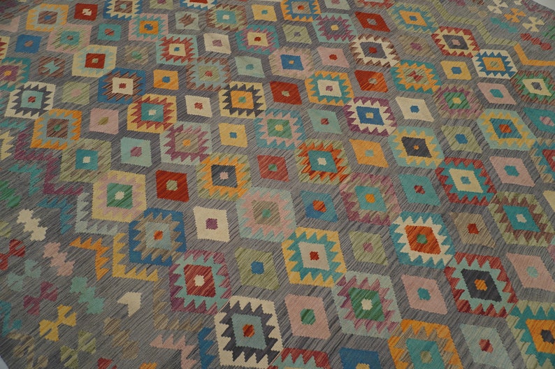 May include: A colorful rug with a geometric pattern in shades of blue, green, red, yellow, and orange. The rug has a gray background and a diamond-shaped pattern.