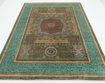Può includere: Un tappeto con motivo turchese, verde, rosso e oro con un medaglione centrale e disegni intricati sul bordo.