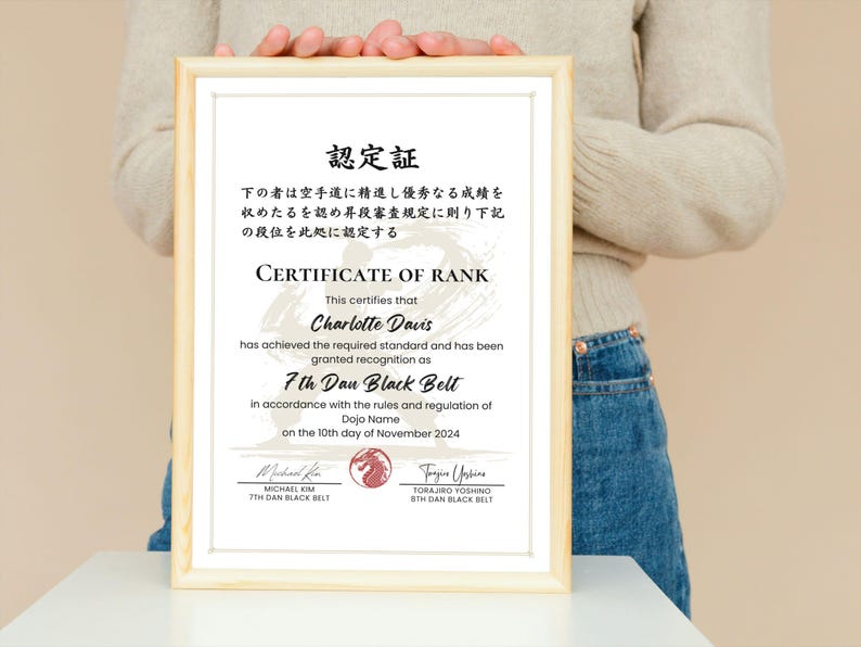 May include: A framed certificate with a light wood frame. The certificate reads "CERTIFICATE OF RANK" and certifies Charlotte Davis as a 7th Dan Black Belt. The date on the certificate is November 10th, 2024.