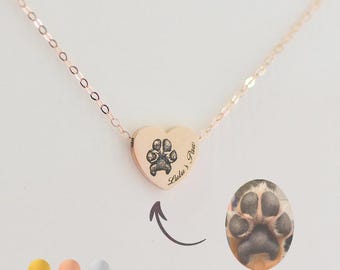 May include: Rose gold heart pendant necklace with a paw print design. The pendant has the text "Lulu's Paw" and an image of a paw print. An additional image of a paw print is shown next to the pendant.