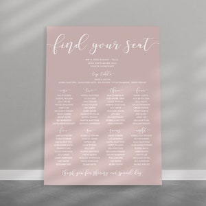 May include: A blush pink wedding seating chart with white text. The chart is titled "Find Your Seat" and lists the names of guests at each table. The top table includes the bride and groom's names, along with the names of their wedding party.
