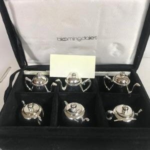 May include: A set of six silver-plated teacups and saucers in a black velvet box. The box has a white label with the text "Bloomingdale's".