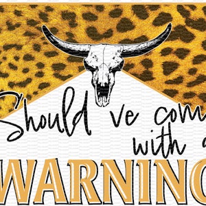 May include: A graphic design with a yellow and black leopard print background. A white bull skull with horns is centered at the top of the design. The text "Should we come with a WARNING" is written in black below the skull.