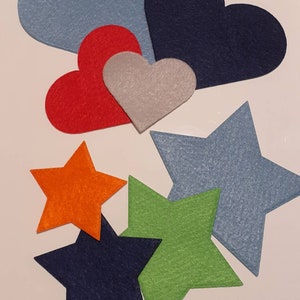 May include: A set of felt shapes in various colours, including blue, red, grey, orange, green, and navy. The shapes include hearts and stars.