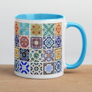 Può includere: Una tazza in ceramica bianca con un bordo e un manico blu. La tazza presenta un motivo colorato di 25 piastrelle quadrate diverse con disegni geometrici.