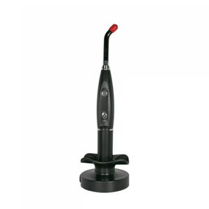 May include: A black dental curing light with a red tip, resting in a black charging base. The device has two buttons and an LED indicator. The curing light is designed for dental procedures.