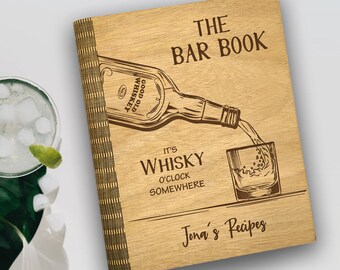 May include: Wooden bar book with an engraved whiskey bottle pouring into a glass. The cover reads "The Bar Book" and "It's Whisky O'Clock Somewhere." The book has a decorative spine and the words "Jona's Recipes" are at the bottom.
