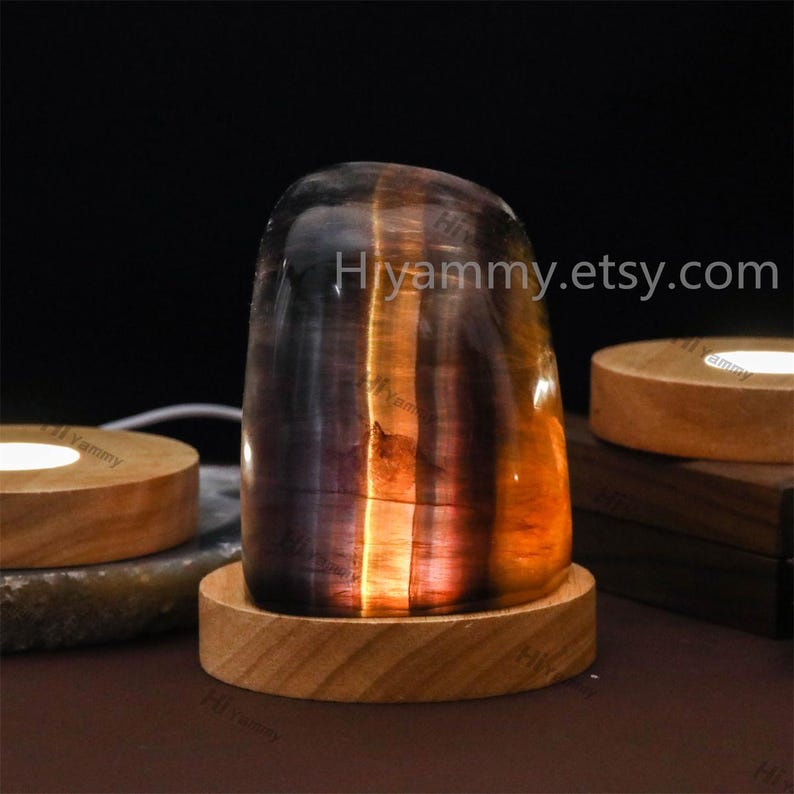 May include: A crystal lamp with a wooden base. The crystal is a mix of purple, blue, and orange colors. The lamp is lit and glowing. The text "Hyammy.etsy.com" is visible in the image.
