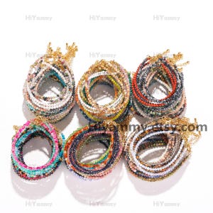 May include: A collection of colorful beaded bracelets with gold clasps. The bracelets are stacked in a circular pattern, showcasing a variety of colors and textures.