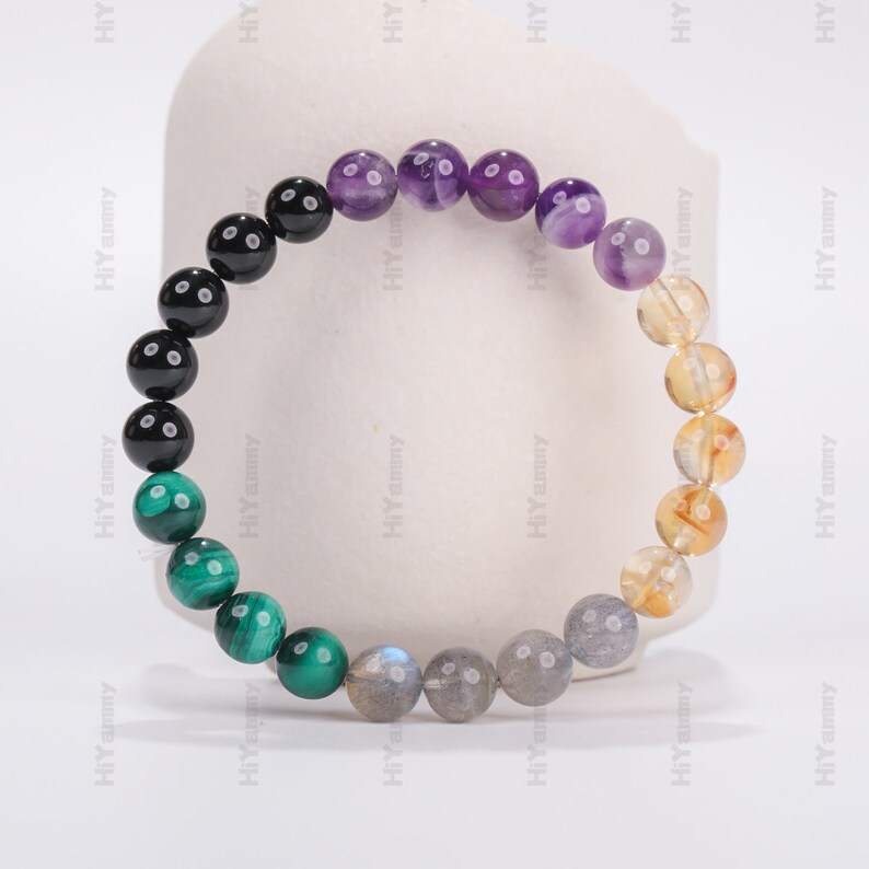 May include: A beaded bracelet with black, green, gray, purple, and yellow beads.
