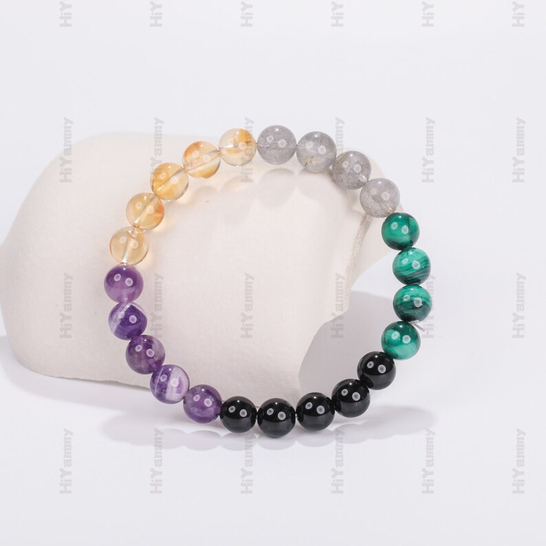 May include: A multi-colored beaded bracelet with yellow, grey, purple, black, and green beads.