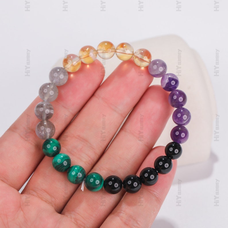 May include: A multi-colored beaded bracelet with yellow, gray, green, purple, and black beads.