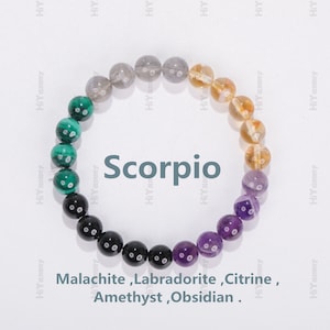 Può includere: Un braccialetto fatto di perline di malachite verde, labradorite grigia, citrino giallo, ametista viola e ossidiana nera. Il braccialetto è disposto in un cerchio e le perline sono separate da piccole perline argentate. Il braccialetto è etichettato "Scorpione".