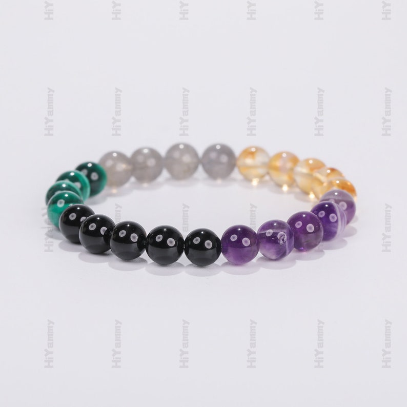 May include: A beaded bracelet with green, black, gray, yellow, and purple beads. The beads are arranged in a gradient pattern.