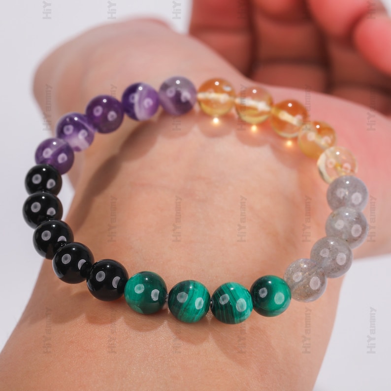 May include: A multi-colored beaded bracelet with black, green, yellow, purple, and gray beads. The bracelet is made of natural stones.