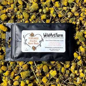 May include: A black package of dried buds labeled "!FREAKS! Electric Buzz Buds" from Wild Art Farm. The package is surrounded by yellow and green dried buds. The label includes the text "Slow Dried & Naturally Cured".