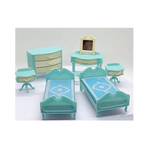 Puede incluir: Un juego de dormitorio de muñecas en miniatura en azul pastel y crema. El juego incluye dos camas, una cómoda, un tocador, dos mesitas de noche y un espejo. Las camas tienen ropa de cama azul estampada.