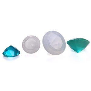 Può includere: Quattro gemme sfaccettate nei toni del blu, del verde acqua e del trasparente. Le gemme sono disposte in fila su uno sfondo bianco. Le gemme variano per dimensioni e forma, con forma rotonda e ovale.