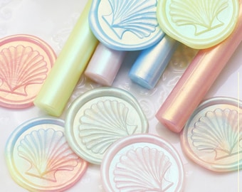 May include: An assortment of iridescent wax seal stamps and sticks in pastel shades of pink, blue, and yellow. Each stamp displays a seashell design. The text "Stamp Polarized Color Change Effect" is visible.