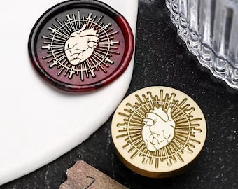 May include: Two wax seals with a heart surrounded by a circle of swords. One seal is red and black, the other is gold.