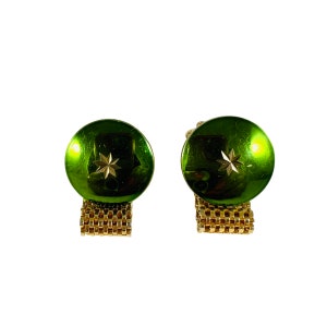 May include: A pair of gold cufflinks with green round faceted glass tops. Each top has a gold star design.