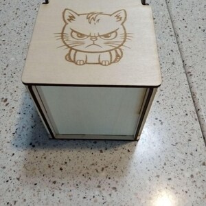 May include: A wooden box with a hinged lid. The lid has a laser-engraved image of a cartoon cat with an angry expression.