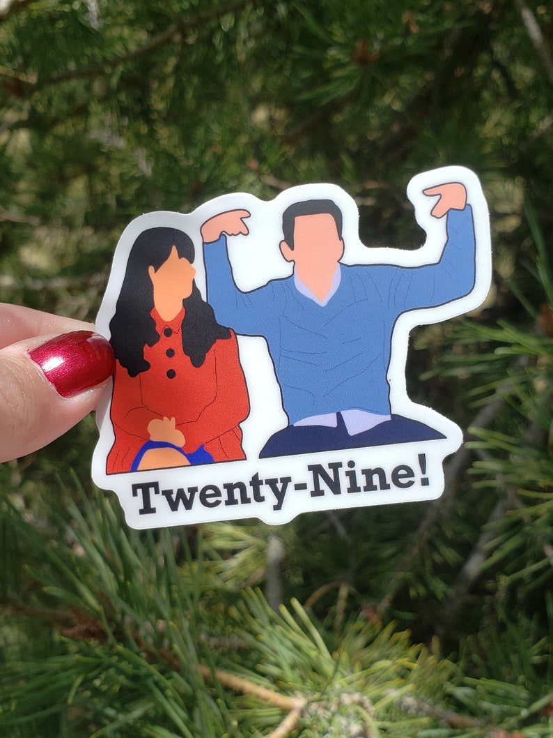 May include: A sticker featuring a cartoon illustration of two people, a woman in a red coat and a man in a blue jumper, with the text "Twenty-Nine!" below them.